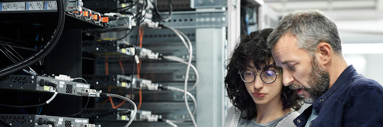 Ein Mann und eine Frau kontrollieren die Hardware der IT in einem Systemraum