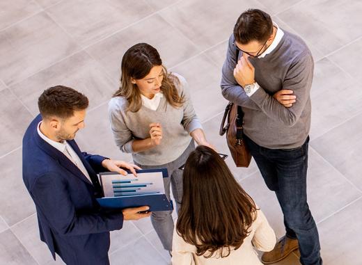 Vier Geschäftsleute analysieren Grafiken und halten eine Besprechung ab